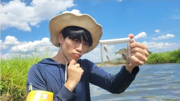 川で捕まえた魚をケースに入れて見せるマーシー